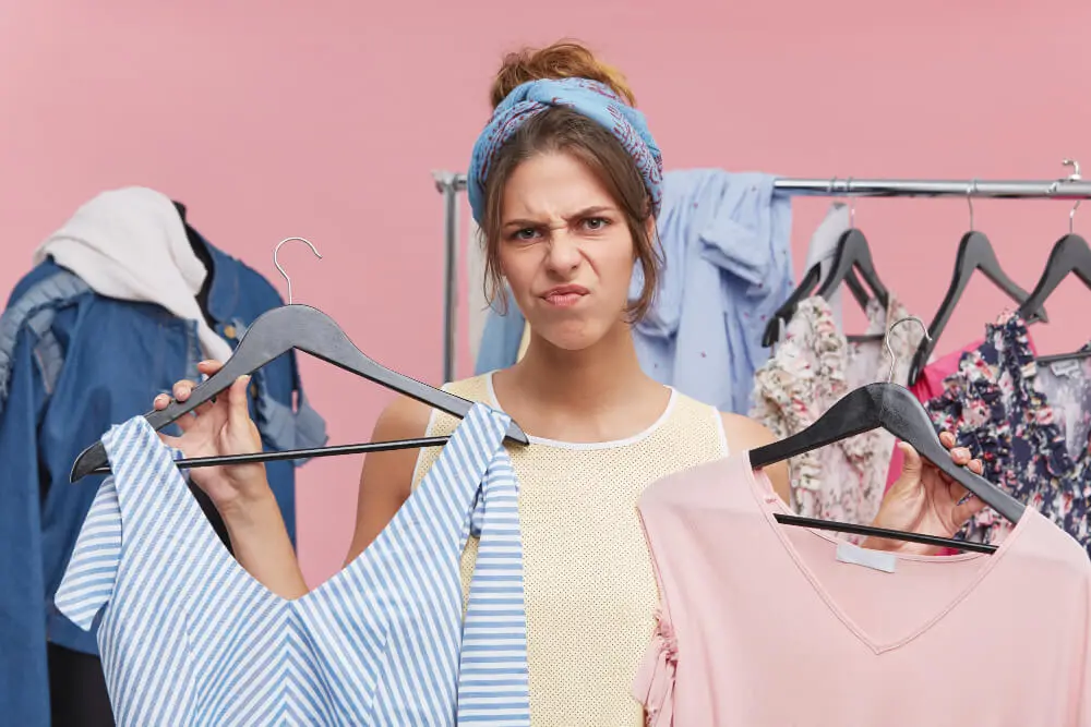 Colloquio di lavoro..come mi vesto? L'immagine rappresenta una donna con degli abiti in mano ed'è indecisa su cosa indossare